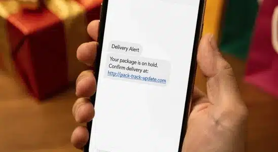 Smartphone displaying a fake shipping text message next to wrapped holiday packages