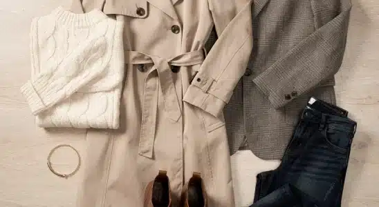 Curated fall capsule wardrobe pieces laid out with sweaters, outerwear, denim, and ankle boots