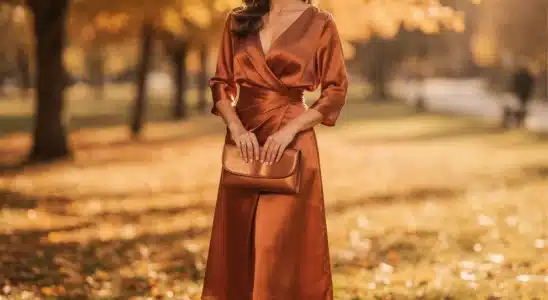 Woman wearing a burnt orange dress as a stylish guest at an outdoor fall wedding.