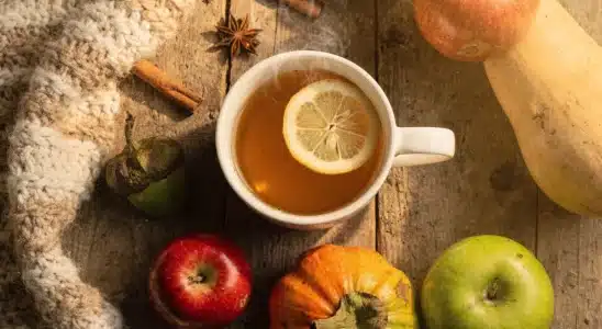 Herbal tea with lemon and fresh autumn produce arranged on a wooden table